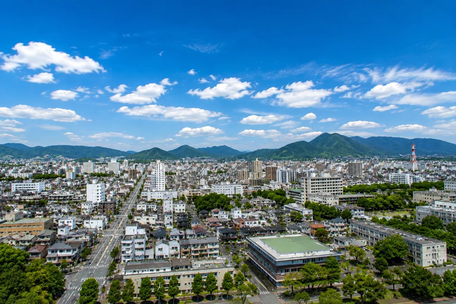 青空と緑の山々を望む街並みのイメージ